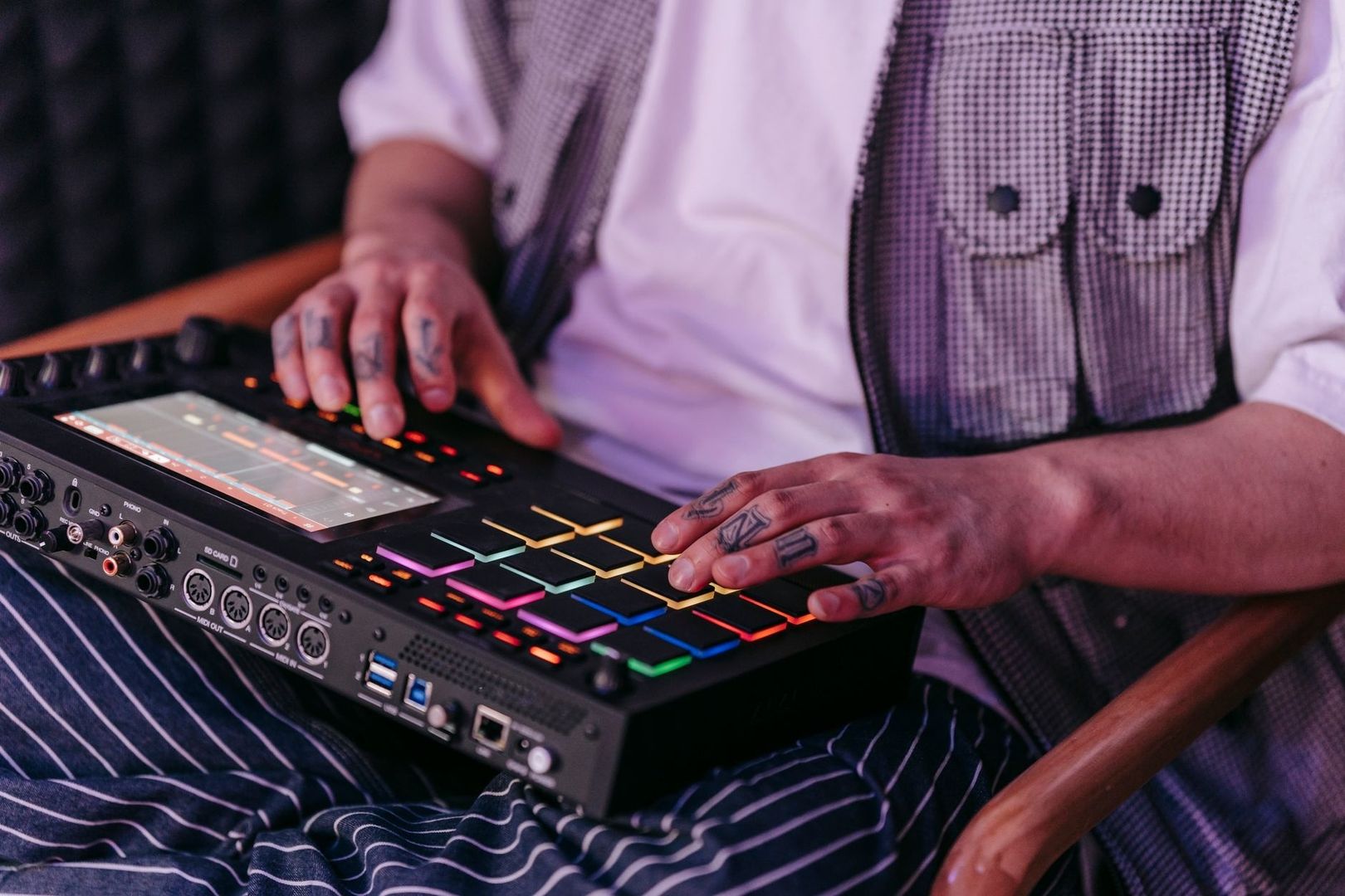 Musikproduzent bedient einen beleuchteten Sampler mit Pads und Display